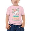 A toddler wearing a pink 'Dream Believe Achieve' Unicorn T-shirt.