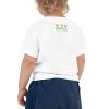 A child, with dreams in their eyes, is dressed in a 'Dream Believe Achieve' Unicorn T-shirt and blue shorts.