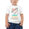 A toddler wearing a 'Dream Believe Achieve' Unicorn T-shirt.