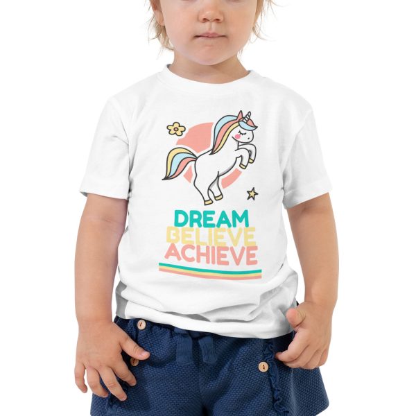 A toddler wearing a 'Dream Believe Achieve' Unicorn T-shirt.